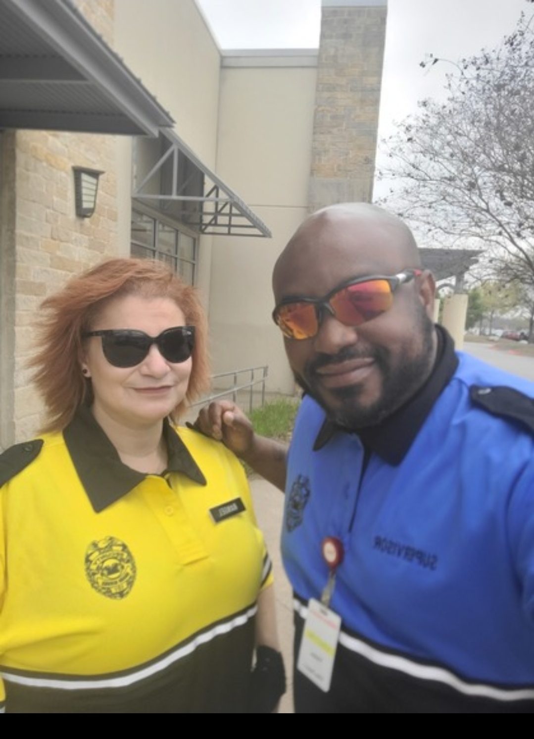 Two security staff in uniform polos standing outside a building